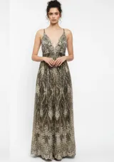 Vestido largo de fiesta confeccionado en tela mesh con acabado glitter. Presenta un diseño con escote en V profundo, breteles finos y falda amplia con caída fluida.