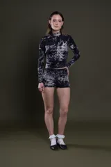 Remera de lycra estampada con patrón batik en blanco y negro, de corte ajustado, cuello alto y mangas largas.