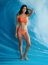 Conjunto de bikini color naranja, compuesto por un corpiño asimétrico de un solo hombro con lazo decorativo y una bombacha colaless.