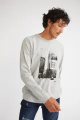 Remera de manga larga color gris melange, con cuello redondo y estampado gráfico en blanco y negro de la ciudad de Nueva York en el frente.