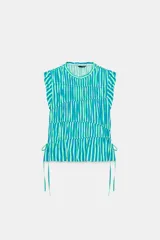 Top sin mangas de cuello redondo, con estampado de rayas verticales en tonos verdes, azules y blancos. Presenta volantes en las sisas, costuras fruncidas en el cuerpo y detalles de lazos ajustables en el bajo.