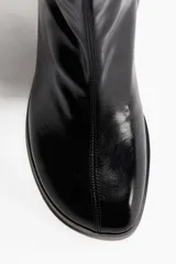 Botines negros de diseño ajustado con acabado brillante, punta cuadrada, costura frontal central y tacón grueso.