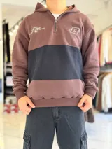 Hoodie de felpa con capucha y medio cierre frontal, diseño en bloques de color celeste y blanco, con bordados decorativos en el pecho.