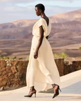 Vestido largo color crudo, confeccionado en viscosa satinada de inspiración grecorromana. Cuenta con escote en V profundo con ribete negro en contraste, mangas cortas fluidas con detalles oscuros, y corte en la cintura con drapeado suave.
