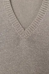 Sweater de punto grueso color beige, con cuello en V profundo y mangas largas. Cuenta con terminaciones acanaladas en el cuello, los puños y el ruedo.