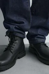 Bota tipo derby con cordones, confeccionada en material liso con horma redonda y suela track con volumen.