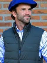 Chaleco acolchado de color azul marino, con cierre frontal completo y cuello alto. Presenta un diseño de costuras horizontales y logo bordado en el pecho.