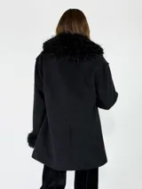 Chaqueta midi color crudo con detalles de piel sintética en el cuello y los puños. Presenta un diseño abierto con bolsillos laterales y una textura suave.