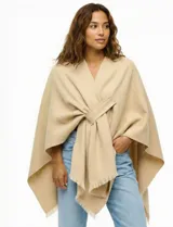 Ruana de tejido soft color negro, con cuello en V y un nudo o pasador frontal que ajusta la prenda. Los bordes tienen terminación desflecada.