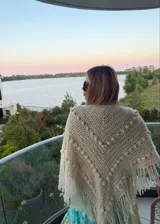 Ruana tejida artesanalmente en color crudo, con diseño triangular, textura de puntos en relieve y terminación con flecos largos en todo el borde.