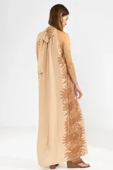 Vestido largo color beige con estampado floral marrón, corte recto, cuello halter y espalda descubierta.