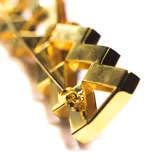 Broche dorado vintage con forma geométrica y resina negra en el centro.