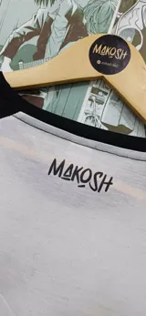 Remera blanca de mangas negras ranglán con estampado de Hello Kitty disfrazada de Superman, Batman y Wonder Woman.