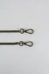 Cartera mini hobo estructurada de cuero negro, decorada con arandelas metálicas doradas en toda la superficie. Cuenta con asa corta de mano y correa de cadena metálica extraíble.