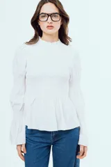 Camisa blanca de manga larga con detalles de nido de abeja en el frente y puños, cuello alto con volados y corte evasé.