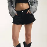 Short de denim negro con diseño de tiro bajo, bolsillos traseros con apliques de strass formando la inscripción "BROOKLYN" y terminaciones deshilachadas.