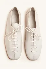 Zapato tipo oxford plano de cuero vacuno en color azul marino, con cordones al tono y suela de cuero.