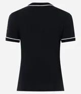 Remera negra de algodón con cuello redondo y mangas cortas con ribete blanco. Presenta un estampado frontal con motivos gráficos inspirados en la película El Diablo Viste a la Moda, incluyendo recortes tipo post-it, ilustraciones y texto.