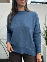 Sweater de punto en color azul jean, con cuello redondo y puños acanalados. Presenta un diseño de corte holgado y textura suave.