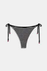 Tanga de bikini con patrón de ondas en blanco y negro, tiras laterales ajustables con pequeños dijes en forma de corazón rojo en los extremos.