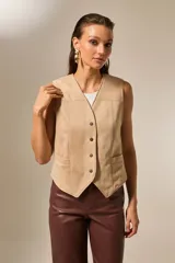 Chaleco sin mangas confeccionado en suede, con escote en V, cierre frontal con botones metálicos y bolsillos laterales.
