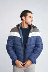 Campera inflada de abrigo para hombre, con capucha desmontable, cierre frontal completo, bolsillos con cierre y logo estampado. Diseño color block en azul, blanco y gris.