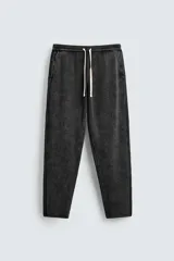 Pantalón relaxed fit tejido en hilatura de algodón de color negro con efecto desteñido. Cuenta con cintura elástica ajustable con cordón en contraste, bolsillos de vivo frontales y detalle de bolsillo trasero de vivo.