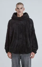 Hoodie oversize tipo anorak confeccionado en piel sintética de corderito, color negro. Presenta cierre central parcial, capucha ajustable con cordones y bolsillo canguro frontal.