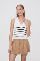 Top blanco de tejido de punto acanalado, sin mangas, con cuello polo y rayas horizontales negras.