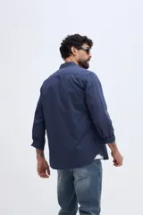 Camisa de twill azul marino con mangas largas, bolsillo en el pecho y botones contrastantes.