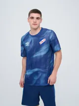 Remera de entrenamiento Umbro del Club Nacional de Football, modelo Press, para hombre. Diseño en tonos de rojo con patrón estampado tipo humo o abstracto, cuello redondo y mangas cortas. Incluye el logo de Umbro y el escudo del club en el pecho.