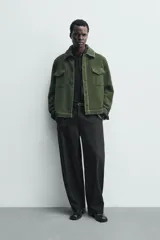 Sobrecamisa de hombre relaxed fit color verde oscuro, confeccionada en tejido de textura efecto toalla. Cuenta con cuello solapa, manga larga con puño abotonado, bolsillos de parche con solapa en el pecho, pespuntes a contraste y cierre frontal con botones.
