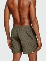 Traje de baño tipo short de hombre, color verde oliva, con estampado repetitivo de la marca en tono más oscuro.
