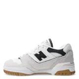 Championes urbanos New Balance modelo 550, color blanco con detalles en negro y gris, confeccionados en cuero sintético y textil, con logo "N" característico en los laterales y suela de goma color caramelo.