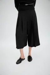 Bermuda larga de tiro medio en color beige, con diseño de pinzas frontales y costuras marcadas. Presenta un corte amplio y cierre lateral con cremallera oculta.