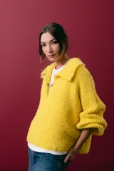 Buzo tejido en mohair de color gris, con silueta amplia y corte en línea A. Presenta cuello tipo remera con broches que permiten cerrarlo como polera, mangas largas con puños y un diseño de tejido horizontal.