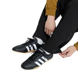 Championes Adidas de estilo tenis, color negro con tres franjas laterales blancas y talón blanco con logo. Suela de goma color caramelo.