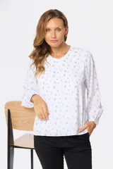 Blusa de manga larga blanca con estampado floral en negro, cuello redondo y cierre frontal con botones.