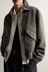 Cazadora de hombre regular fit confeccionada en tejido efecto ante, con acabado lavado, cuello solapa, manga larga, bolsillos de plastrón con solapa en la cadera, detalles elásticos en puños y cintura, y cierre frontal de cremallera.
