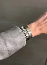 Juego de dos pulseras rígidas plateadas, una con incrustaciones de piedras blancas y otra con perforaciones.