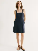 Vestido corto de corte recto con escote cuadrado, tirantes anchos y bolsillos laterales. Diseño minimalista con costura horizontal bajo el busto.