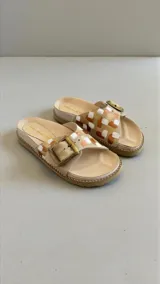 Sandalias planas de cuero color beige con diseño pintado a mano en tonos dorados, marrones y blancos, tira ancha con hebilla metálica grande y plantilla anatómica.