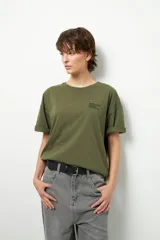 Remerón unisex de manga corta, color verde militar, con cuello redondo y texto pequeño en el pecho que dice "Support Local Artists".