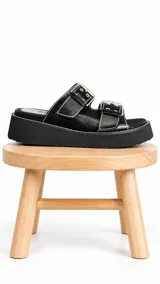 Sandalias negras de 100% cuero con plataforma liviana, dos hebillas regulables y costuras blancas en contraste.