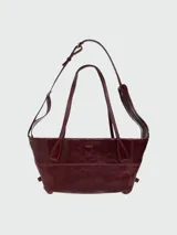 Bolso shoulder bag de Balmain en color bordó, confeccionado en cuero, con doble asa superior y correa ajustable para el hombro. Presenta costuras decorativas y el logo de la marca estampado en tono dorado en la parte frontal.