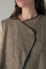 Chaleco corto de lana fina sin teñir, con diseño de solapa cruzada y terminaciones envivadas. Es una prenda reversible, liviana y versátil, ideal para uso diario.