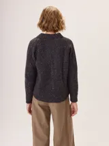 Saco de lana color marrón, de tejido grueso, con cuello redondo y botones frontales. Presenta mangas raglán con detalle de punto acanalado y bolsillos delanteros tipo parche.