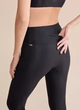 Calza deportiva de tiro alto con diseño de alta compresión y textura acanalada con leve brillo. Cuenta con un bolsillo trasero en la cintura y tecnología de ajuste adaptable.