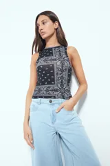 Top crop sin mangas color rojo con estampado tipo bandana en blanco y negro. Tiene cuello cerrado y sisas definidas.