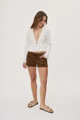 Blusa manga larga de color negro con escote en V profundo y lazo ajustable en el frente, confeccionada en tejido liviano con corte evasé.